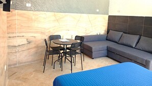 A room with a bed, a sofa, a table with chairs, and a wall with a marble-like pattern. - Terrazza Cristallini Napoli (Naples)