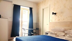 A hotel room with a bed, a desk, a chair, a window with curtains, and a door. - Terrazza Cristallini Napoli (Naples)