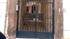 A black wrought iron gate with a keypad lock, set in a stone archway, leading to a building with a tiled entrance. - Terrazza Cristallini Napoli (Naples)