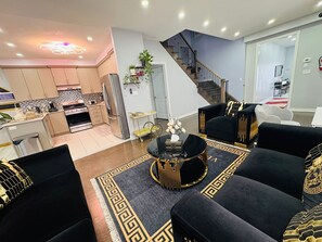 Ein modernes Wohnzimmer mit einem schwarzen Sofa, einem Couchtisch und einer Treppe, die zu einer weiteren Ebene führt.