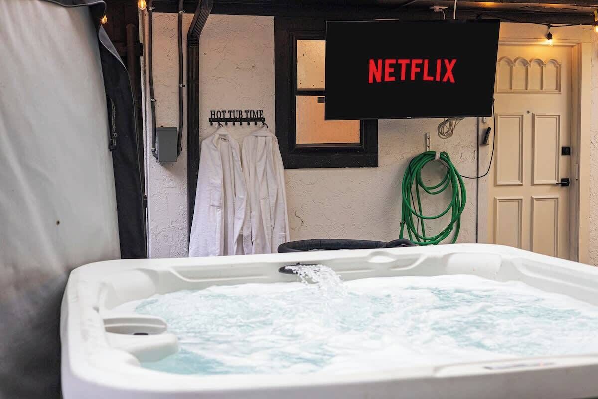 Una vasca idromassaggio con acqua corrente, un cartello con scritto 'NETFLIX' e un portascopevoli con asciugamani.