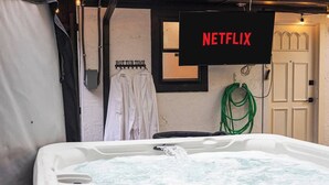 Ein Whirlpool mit fließendem Wasser, ein Schild mit der Aufschrift 'NETFLIX' und ein Handtuchhalter mit Handtüchern.