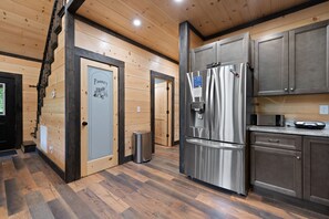 A modern kitchen with wooden paneling, stainless steel appliances, and a pantry door. - Private pickleball / basketball court, hot tub at the Red River Gorge KY (Campton)
