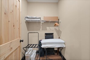 A compact room with a bunk bed, a small shelf with folded clothes, a drying rack, and a suitcase.