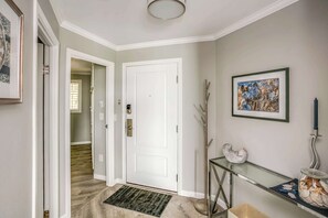A hallway with a white door, a glass console table with decorative items, and a framed picture on the wall. - Gearhart House G637, second floor (Gearhart)