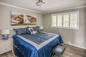 A bedroom with a large bed, two wall-mounted lamps, a window with shutters, and a ceiling fan. - Gearhart House G637, second floor (Gearhart)