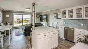 Een moderne keuken met witte kasten, een RVS vaatwasser en een groot raam met uitzicht op de omgeving.