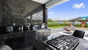 Eine moderne Küche mit Gasherd, eingebauten Geräten und einem großen Fenster mit Blick auf einen Garten.