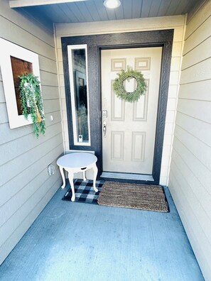 A front entryway with a door, a small table, a doormat, and a wall-mounted plant. - Charming 3-bedroom house with AC in Selah perfect for relaxing, small pets ok (Selah)