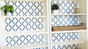 A white shelving unit with a blue wavy pattern, containing a potted plant, a woven basket, and board games. - Charming 3-bedroom house with AC in Selah perfect for relaxing, small pets ok (Selah)