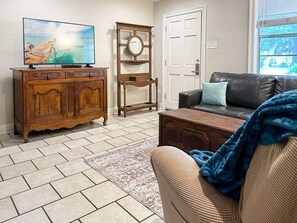 Ein Wohnzimmer mit Fernseher, Holzschrank und einer Couch.