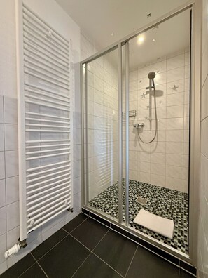A modern shower with a glass door, a tiled floor, and a white towel on the floor. - 2-bedroom Mountain View Apartment with Fireplace (Oberwiesenthal)