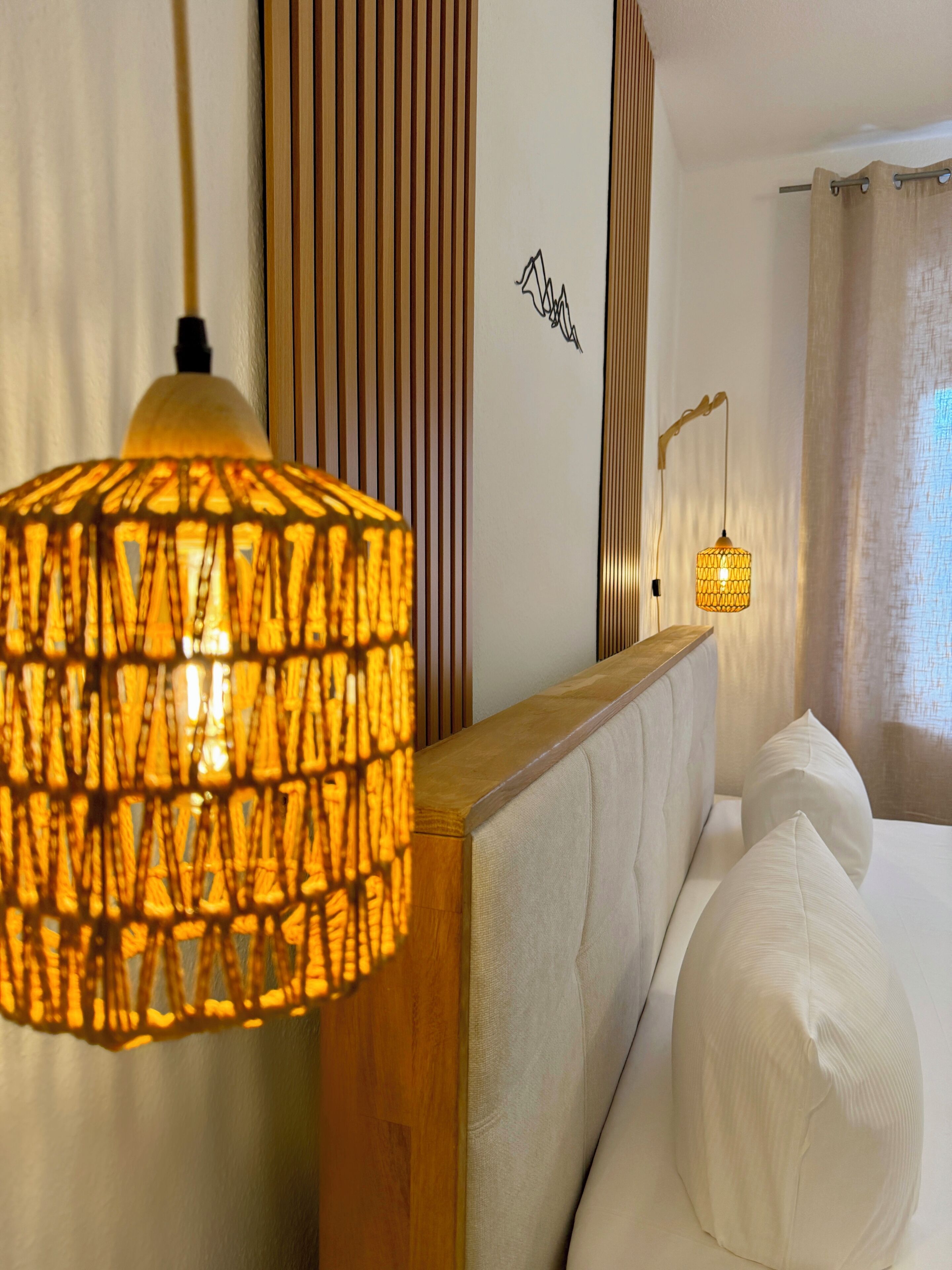 Ein Hotelzimmer mit einem Bett, zwei Nachttischlampen, einer Wand mit vertikalen Holzleisten und einem kleinen Wandbild.