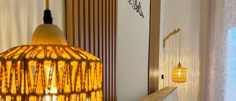 Ein Hotelzimmer mit einem Bett, zwei Nachttischlampen, einer Wand mit vertikalen Holzleisten und einem kleinen Wandbild.