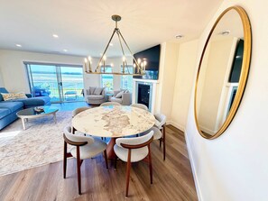 A modern living room with a round table, chairs, a sofa, and a large mirror. - Coastal Elegance - 2BDRM (Nanoose Bay)