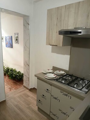 A kitchen with a gas stove, cabinets, and a marble backsplash.