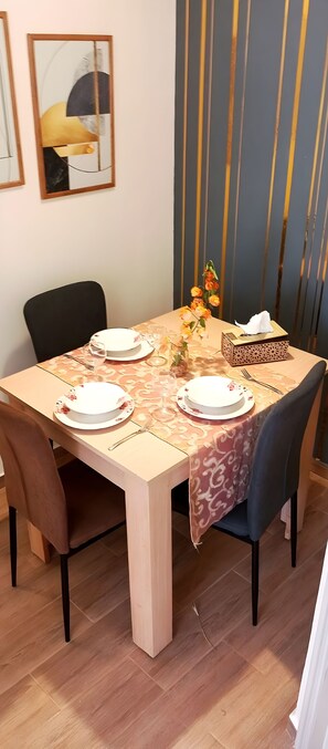 Une table à manger recouverte d’une nappe à motifs floraux, avec des chaises et un vase rempli de fleurs.