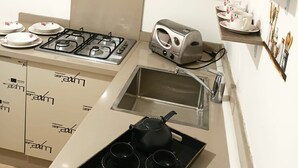 A kitchen with a gas stove, toaster, and a tray with black cups and a teapot.