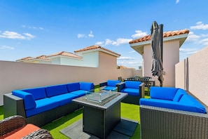 An outdoor patio with wicker furniture, a glass-top coffee table, and a pergola with a canopy.
