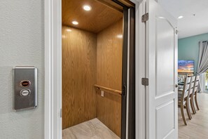 A modern elevator with a wooden interior and a wall-mounted call button.