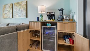 Uma cozinha compacta com cafeteira, liquidificador e mini-geladeira repleta de bebidas.