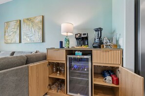 Eine kleine Küchenzeile mit Kaffeemaschine, Mixer und einem Minikühlschrank, gefüllt mit Getränken.
