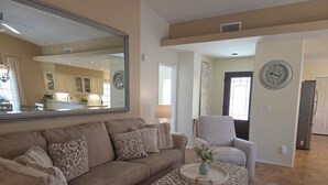 A living room with a sofa, ottoman, and a mirror. - Beautifully decorated single-level private townhome in the heart of Oro Valley. (Tucson)