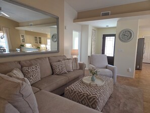 A living room with a sofa, ottoman, and a mirror. - Beautifully decorated single-level private townhome in the heart of Oro Valley. (Tucson)