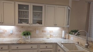 A kitchen with white cabinets, a granite countertop, a sink, and a potted plant. - Beautifully decorated single-level private townhome in the heart of Oro Valley. (Tucson)