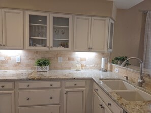 A kitchen with white cabinets, a granite countertop, a sink, and a potted plant. - Beautifully decorated single-level private townhome in the heart of Oro Valley. (Tucson)