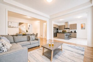A modern living room with a sofa, coffee table, and a dining area with chairs. - Very Modern New Luxury House in RichmondHill (Richmond Hill)