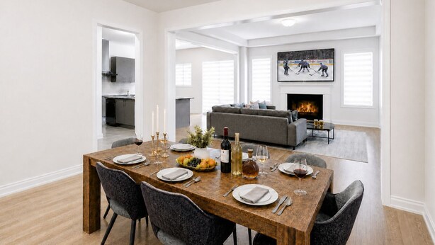 Un comedor con una mesa de madera dispuesta para seis personas, un sofá gris al fondo y una chimenea.