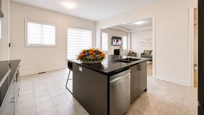 Una cocina moderna con una isla central, una zona de comedor con sofá y un televisor montado en la pared.