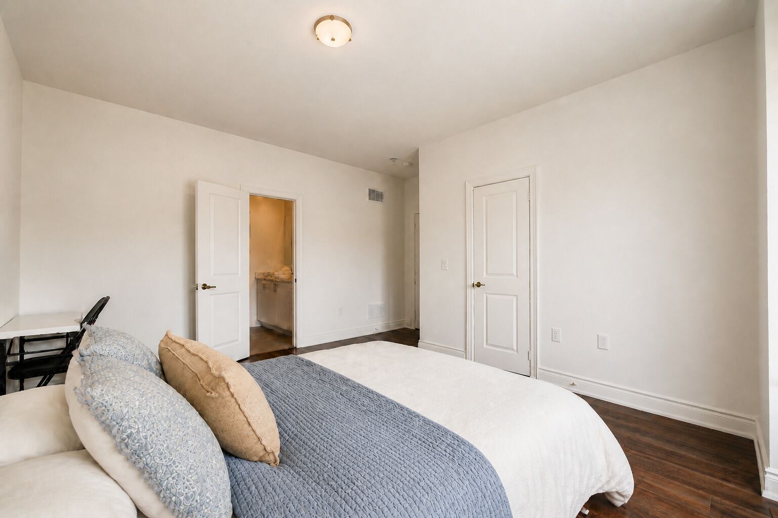 Une chambre à coucher comprenant un lit, un bureau et une porte donnant sur une salle de bain.