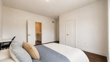 Une chambre à coucher comprenant un lit, un bureau et une porte donnant sur une salle de bain.