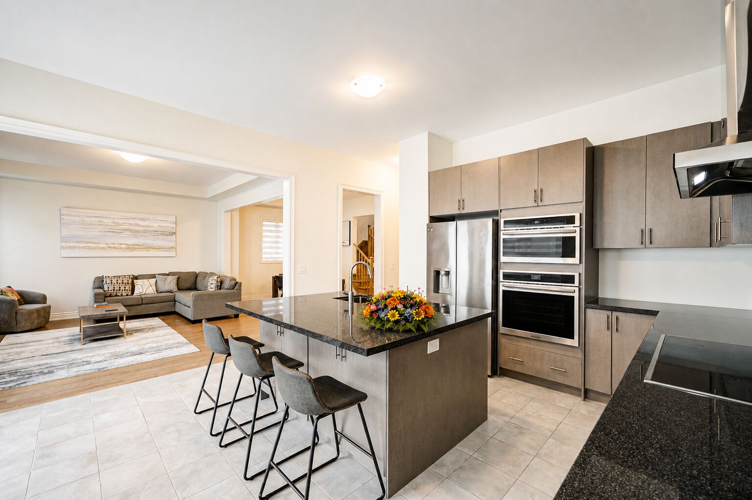 A modern kitchen with a central island, stainless steel appliances, and a dining area with bar stools.