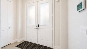 Una puerta blanca con un panel de vidrio esmerilado, un picaporte y un pequeño dispositivo electrónico montado en la pared a su lado.