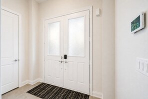A white door with a frosted glass panel, a doorknob, and a small electronic device mounted on the wall beside it.