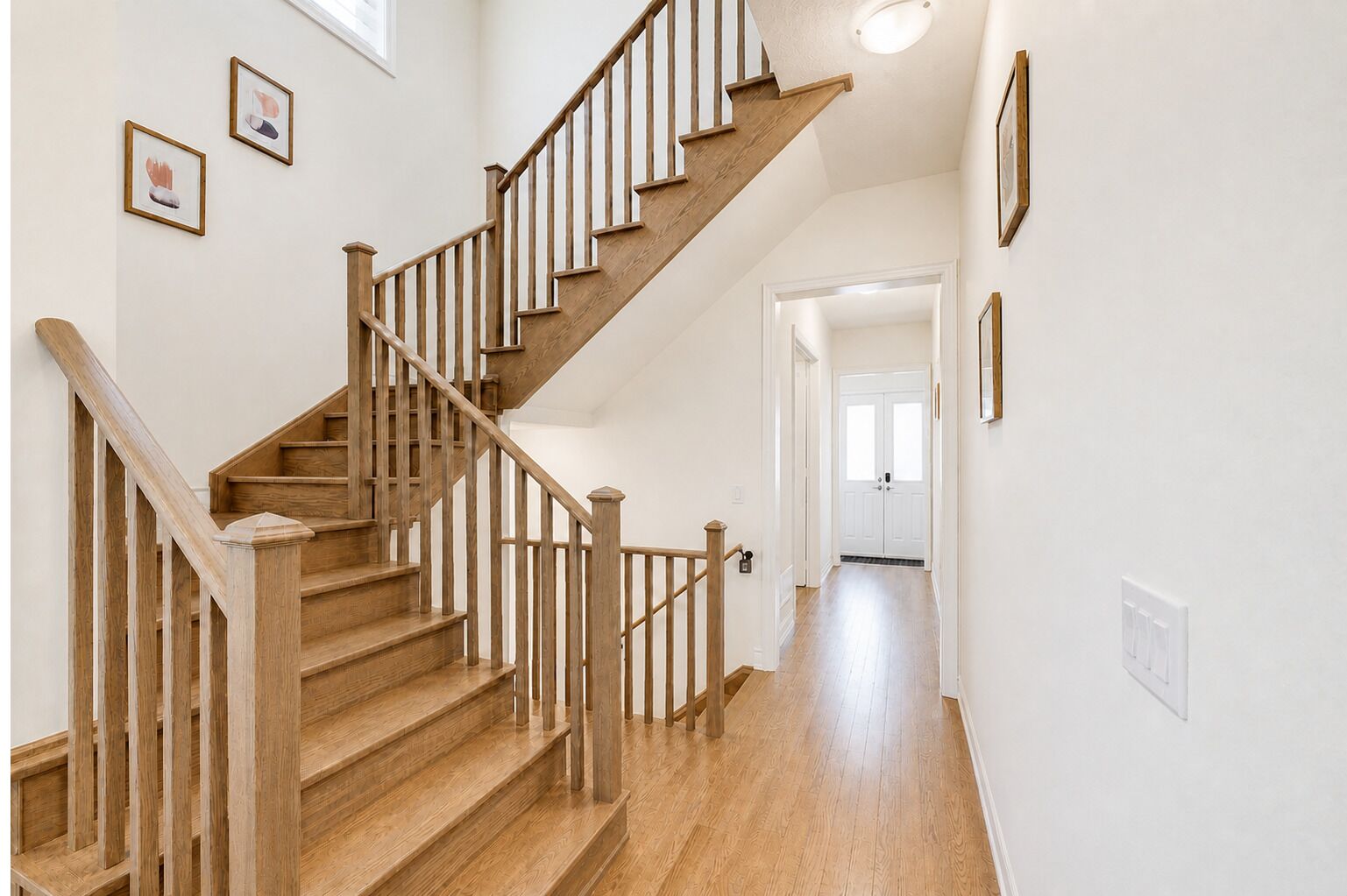 Bright entryway with warm wood floors and a beautiful open staircase