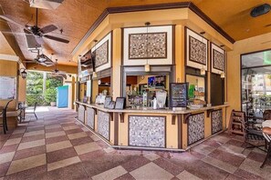 A bar area with a checkered floor, a counter with a menu, and a ceiling fan. - 3BR Resort Suite on I-drive + Pools (Orlando)