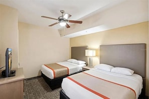 A hotel room with two beds, a ceiling fan, a TV, and a lamp. - 3BR Resort Suite on I-drive + Pools (Orlando)