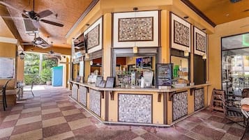 A bar area with a checkered floor, a counter with a menu, and a ceiling fan.