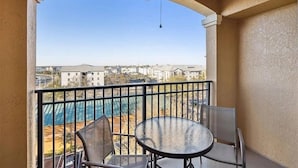 A balcony with a table and chairs, a ceiling fan, and a view of a cityscape. - 3BR Resort Suite on I-drive + Pools (Orlando)