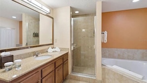 A bathroom with a shower, sink, and bathtub, wooden cabinets, and a large mirror. - 3BR Resort Suite on I-drive + Pools (Orlando)