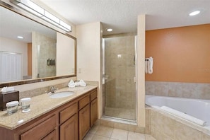 Une salle de bain avec douche, lavabo et baignoire, des meubles en bois et un grand miroir.