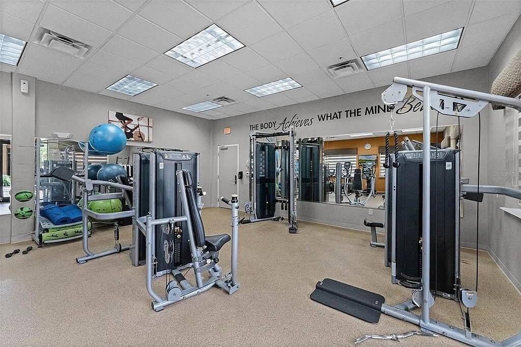Une salle de sport équipée de matériel d’exercice, d’un miroir et d’une citation motivante affichée sur le mur.
