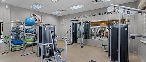 Une salle de sport équipée de matériel d’exercice, d’un miroir et d’une citation motivante affichée sur le mur.