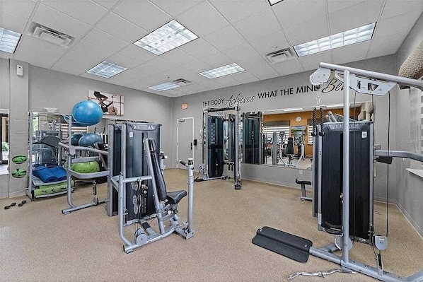 A gym with exercise equipment, a mirror, and a motivational quote on the wall. - 3BR Resort Suite on I-drive + Pools (Orlando)