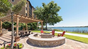 A patio area with a stone fire pit, outdoor seating, and a view of a body of water. - Apartment in Orlando, near the theme parks. (Orlando)