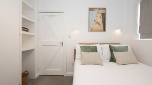 Ein Schlafzimmer mit einem Bett, einer weißen Tür, einem an der Wand befestigten Bild und einem Bücherregal.